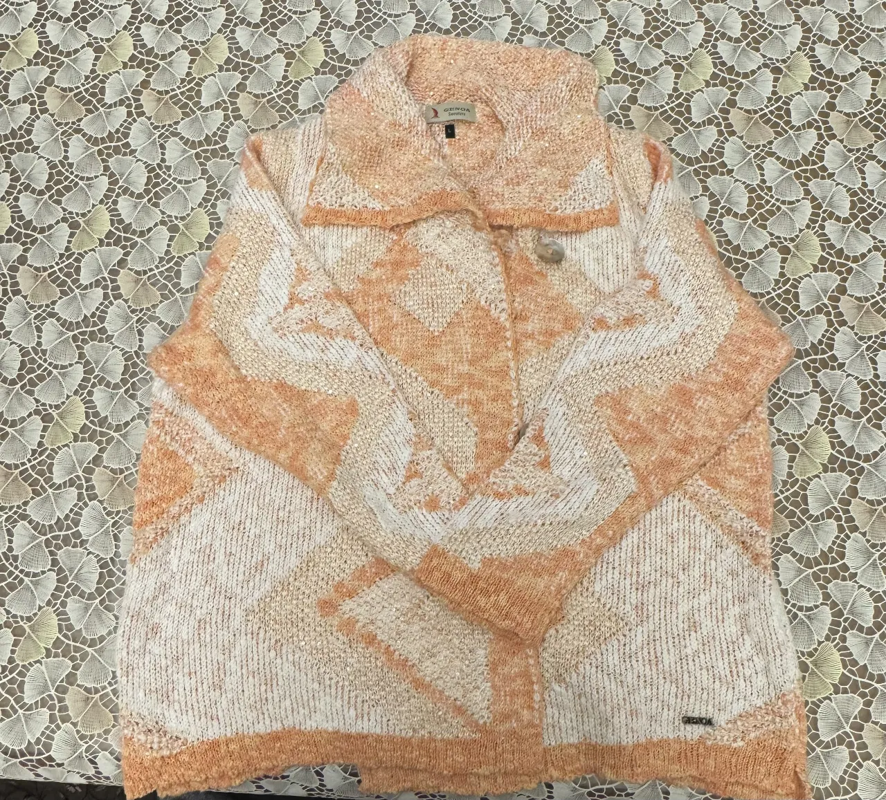 Cardigan de mujer GENOA Sweaters, tejido con diseño geométrico en tonos naranja y blanco. Cuello solapa y cierre con botón. Ideal para un look casual y abrigado.
