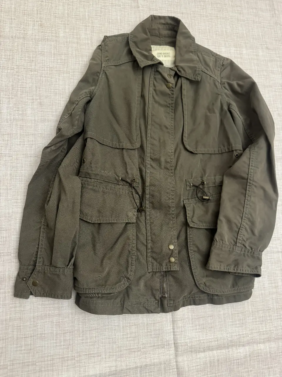 Campera verde militar con múltiples bolsillos y ajuste en la cintura. Ideal para un look utilitario y casual.