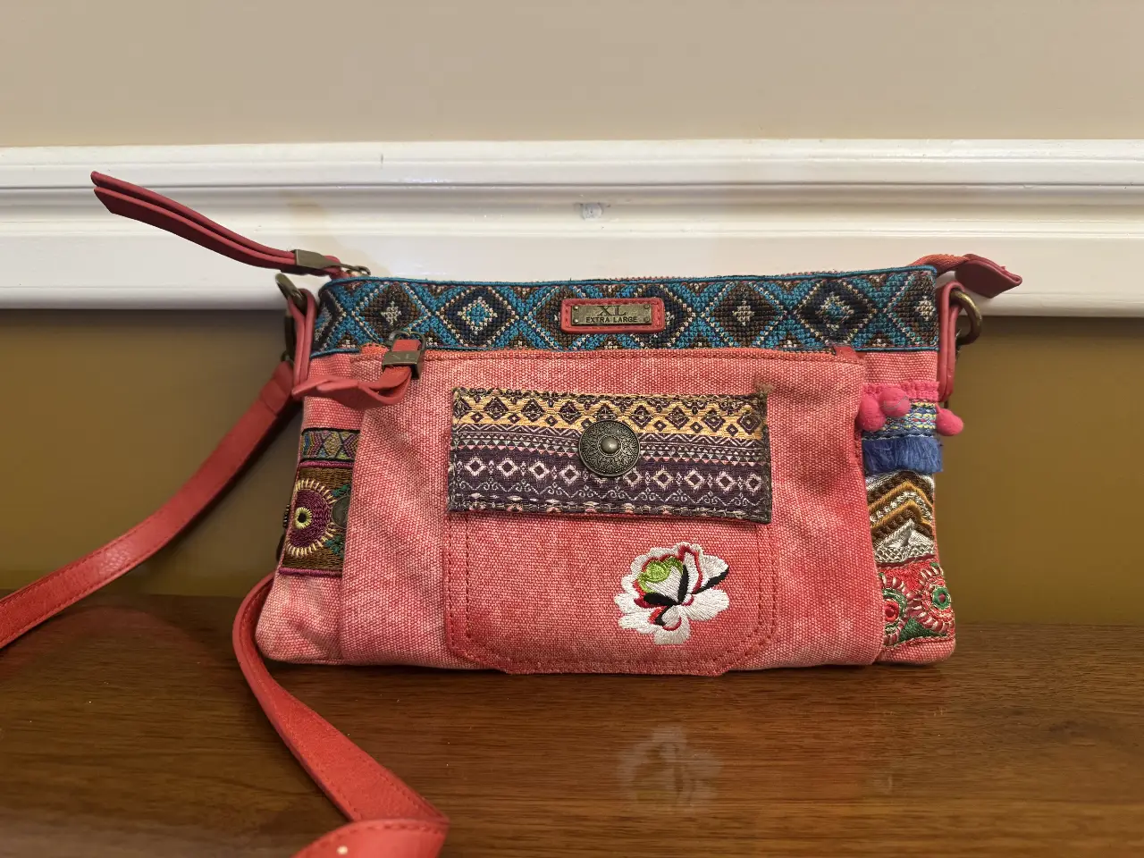 Bandolera de tela roja con detalles bordados y apliques. Diseño artesanal con motivos étnicos y florales. Ideal para un look bohemio y casual.