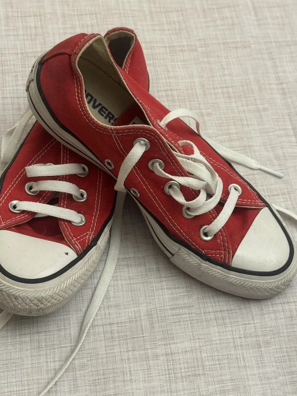 Zapatillas Converse rojas con cordones blancos, ideales para un look casual y urbano. Tienen la clásica puntera blanca y suela de goma.