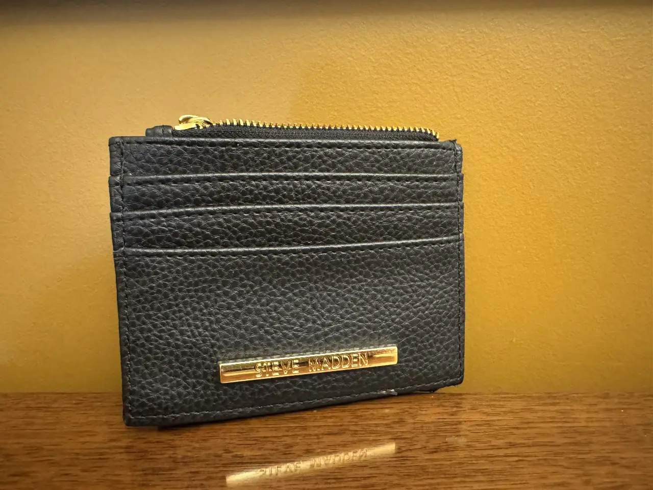 Billetera tarjetero de cuero negro con detalles dorados y cierre. Ideal para llevar tarjetas y efectivo de forma organizada y con estilo. Marca Steve Madden.