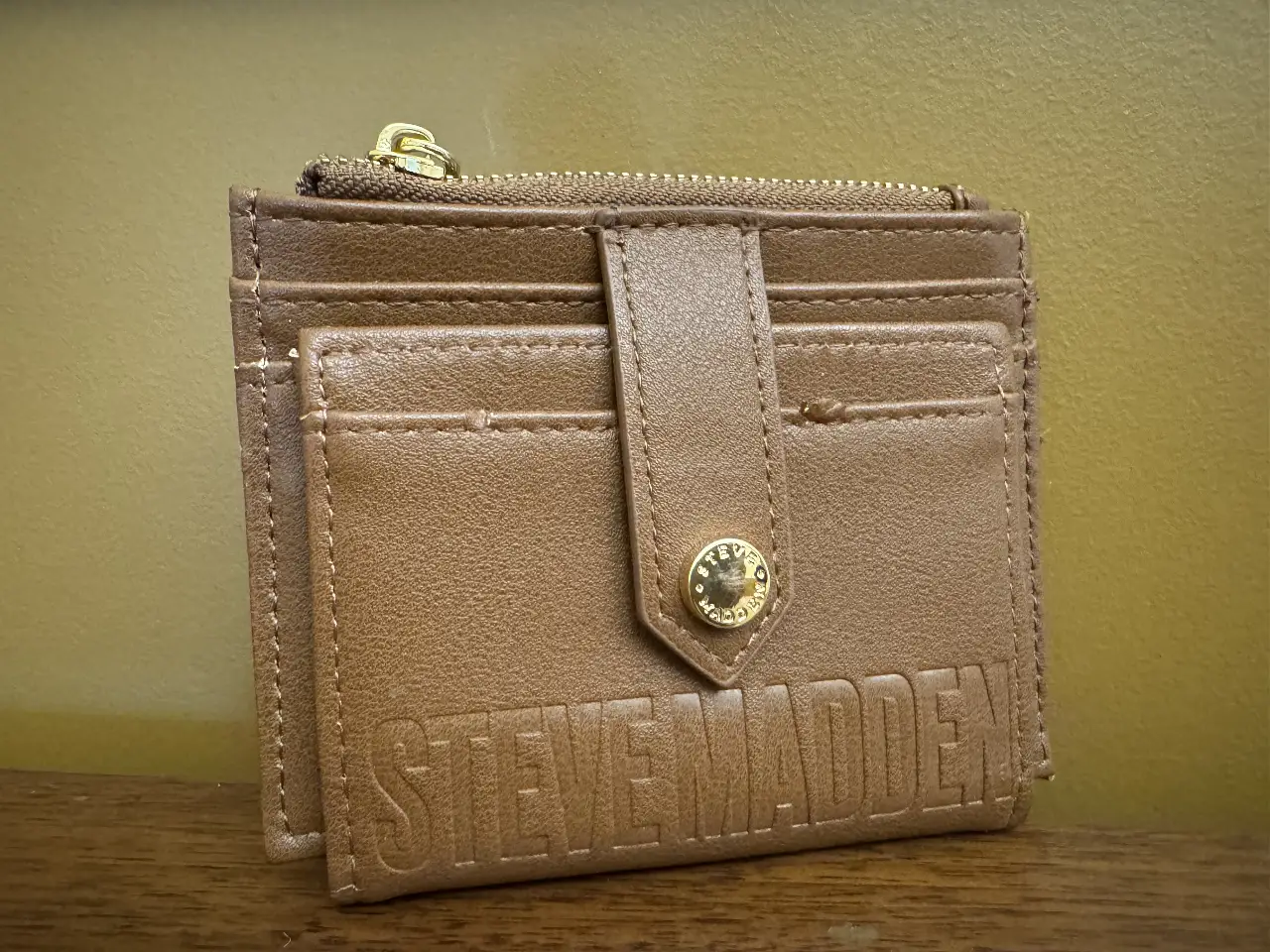 Billetera tarjetero de cuero sintético color marrón, con cierre y botón dorado. Ideal para llevar tarjetas y documentos de forma segura y organizada. Diseño elegante y compacto, perfecto para el uso diario.