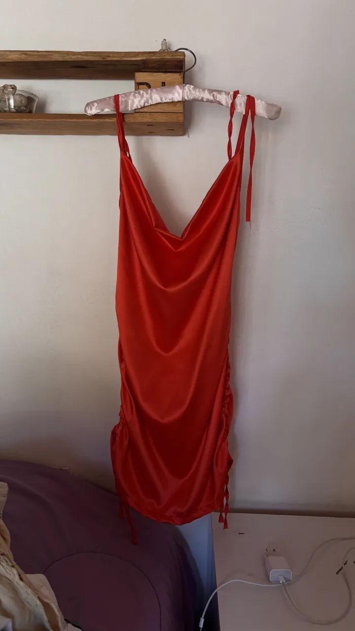 Vestido rojo vibrante, con tiras finas regulables y detalle de fruncido en los laterales. Ideal para una noche de fiesta o una salida especial. Su diseño moderno y sensual te hará destacar.