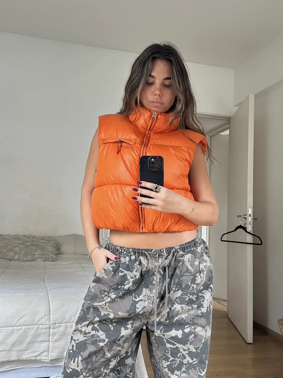 Chaleco crop acolchado naranja con cuello alto y cierre al frente. Posee un bolsillo con solapa en el pecho.