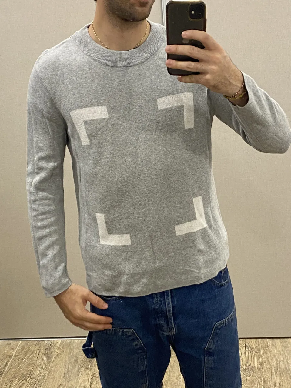 Sweater gris con estampa de figuras geométricas blancas en el frente. Cuello redondo y mangas largas.