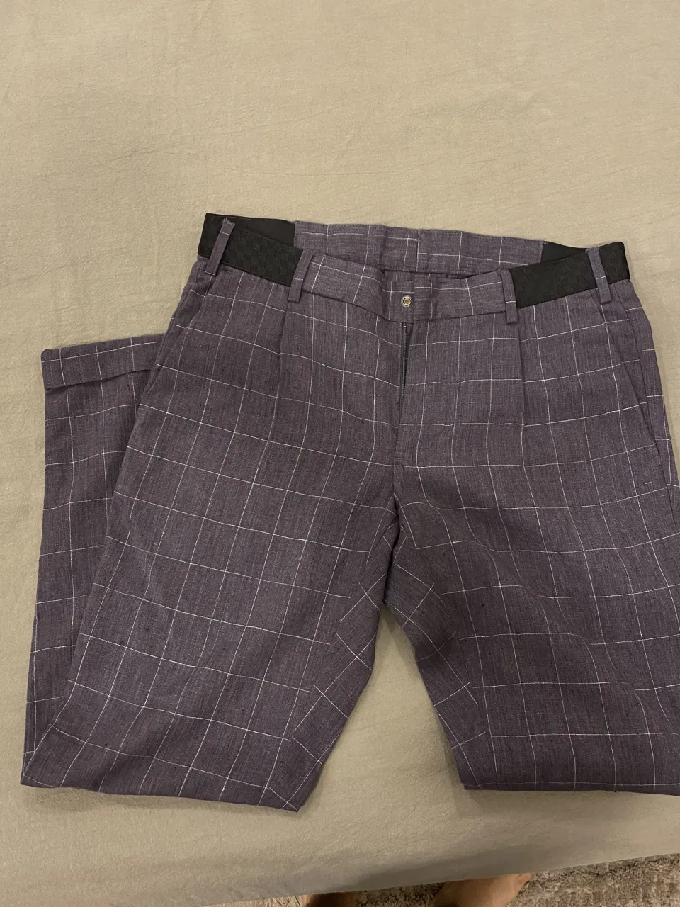 Pantalón de vestir a cuadros grises con líneas blancas finas. Posee bolsillos y cierre.