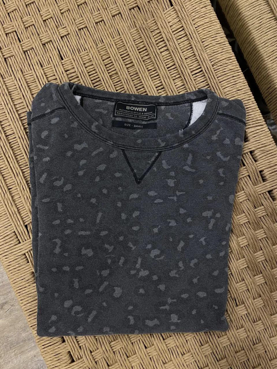 Remera gris con estampa de manchas en tono más oscuro. Cuello redondo con pespunte en V.