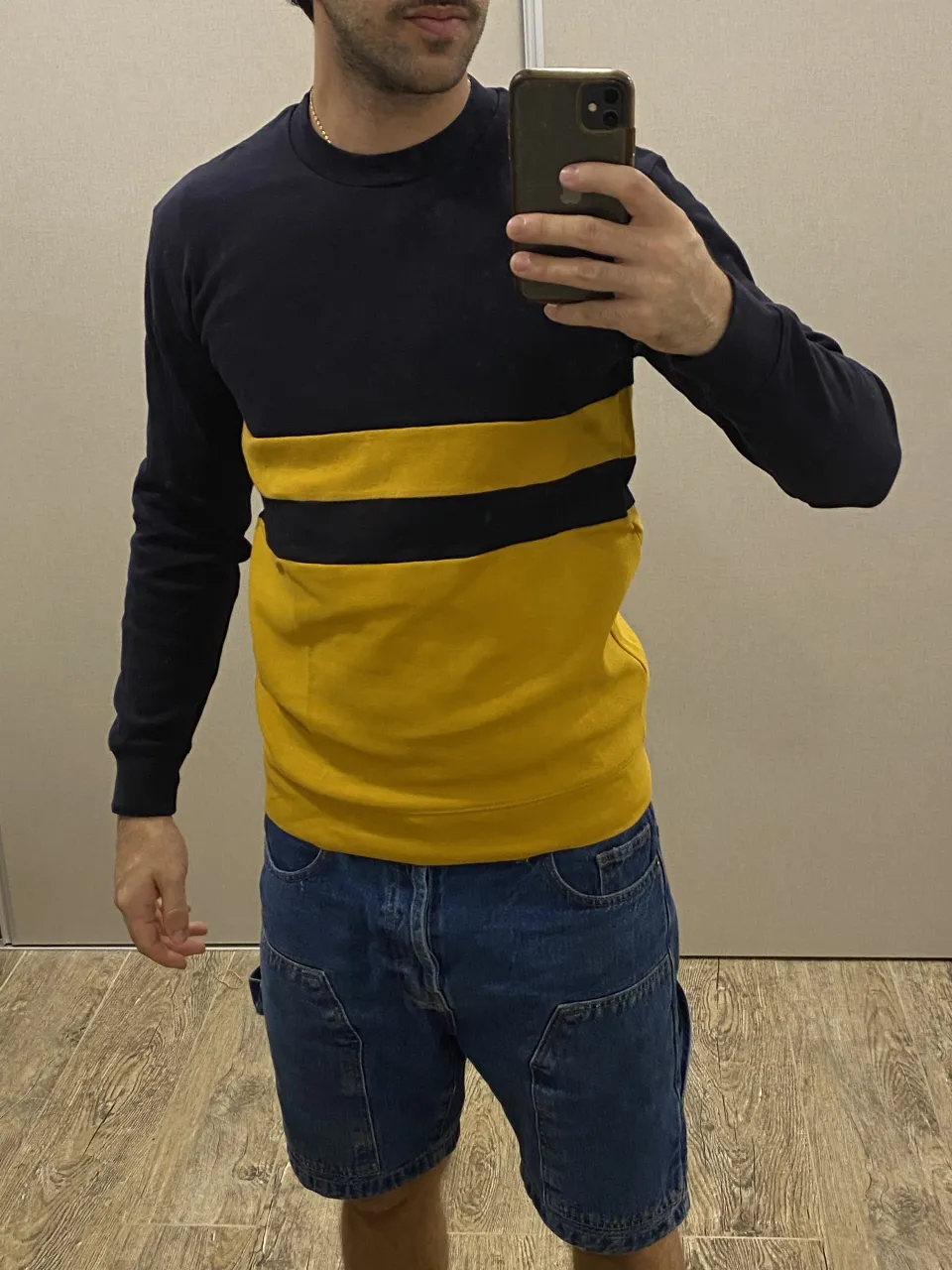 Remera de manga larga con dos franjas horizontales. La parte superior y las mangas son azul marino. La franja central es negra y la parte inferior es amarilla.