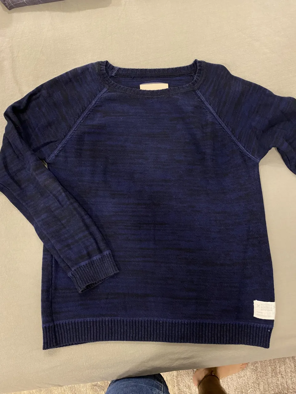 Sweater azul oscuro con detalles en negro, cuello redondo y mangas largas. Posee puños y cintura tejidos.