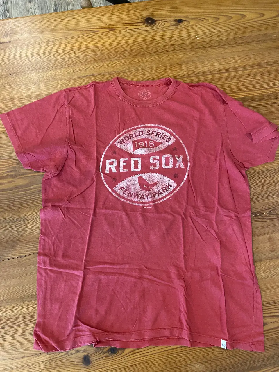 Remera roja de los Red Sox de Boston, con estampado vintage de "World Series 1918" y logo de Fenway Park. Ideal para fanáticos del béisbol y estilo casual.