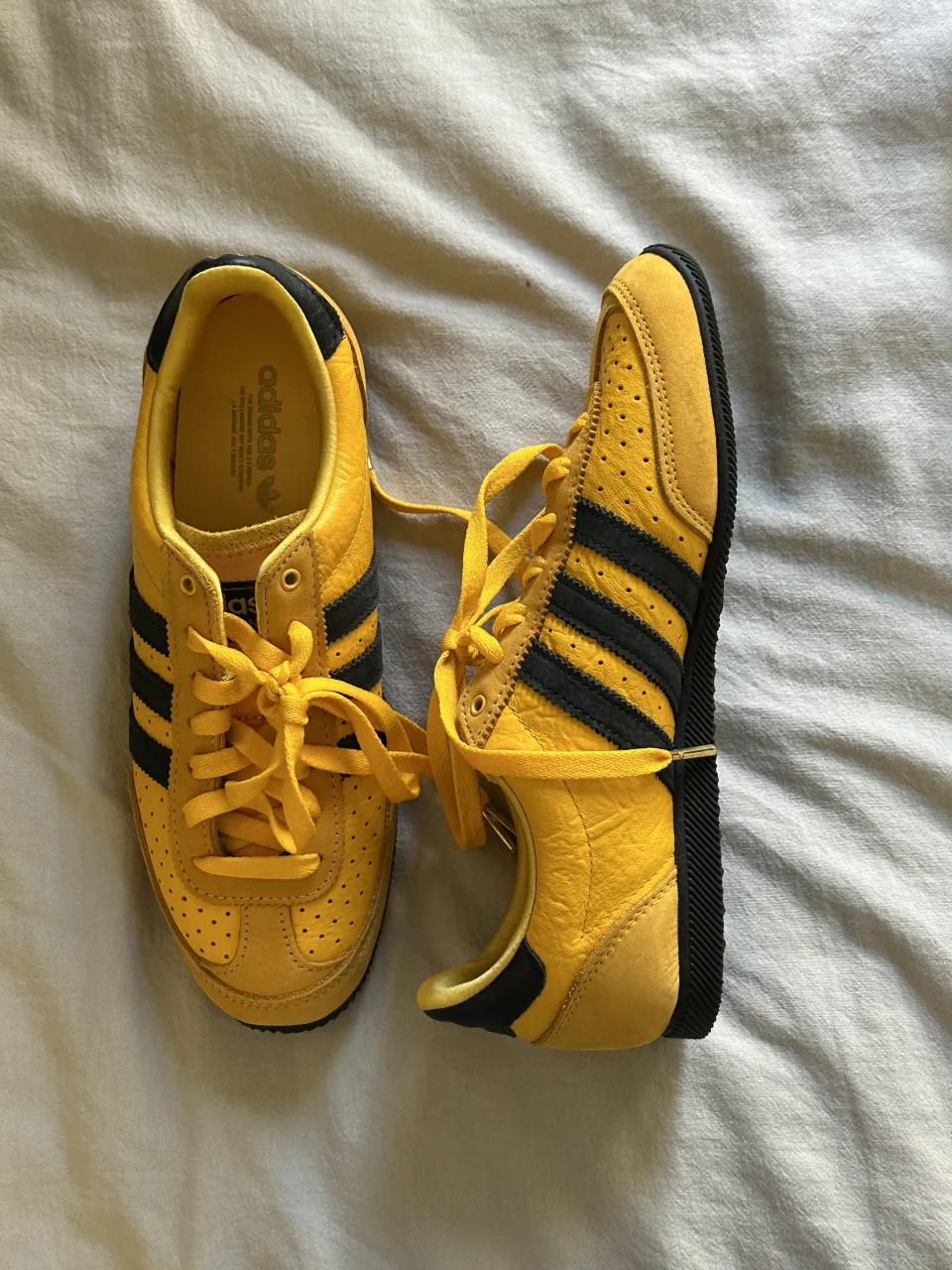 Zapatillas Adidas japan amarillas con detalles en negro y cordones amarillos.