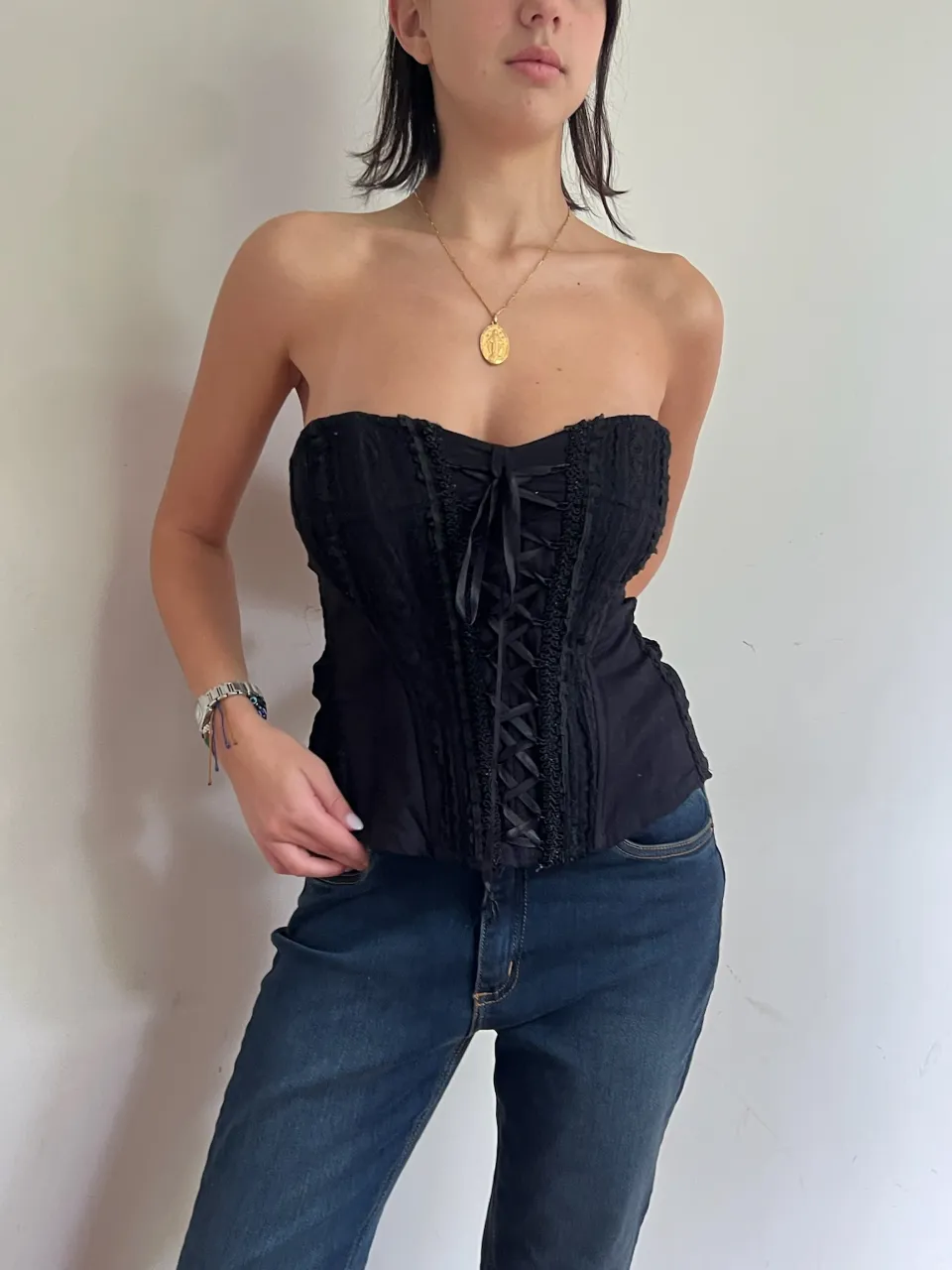 Top negro estilo corset con cordones delanteros y detalles de encaje. Posee tiras finas y cierre en la espalda (fallado).