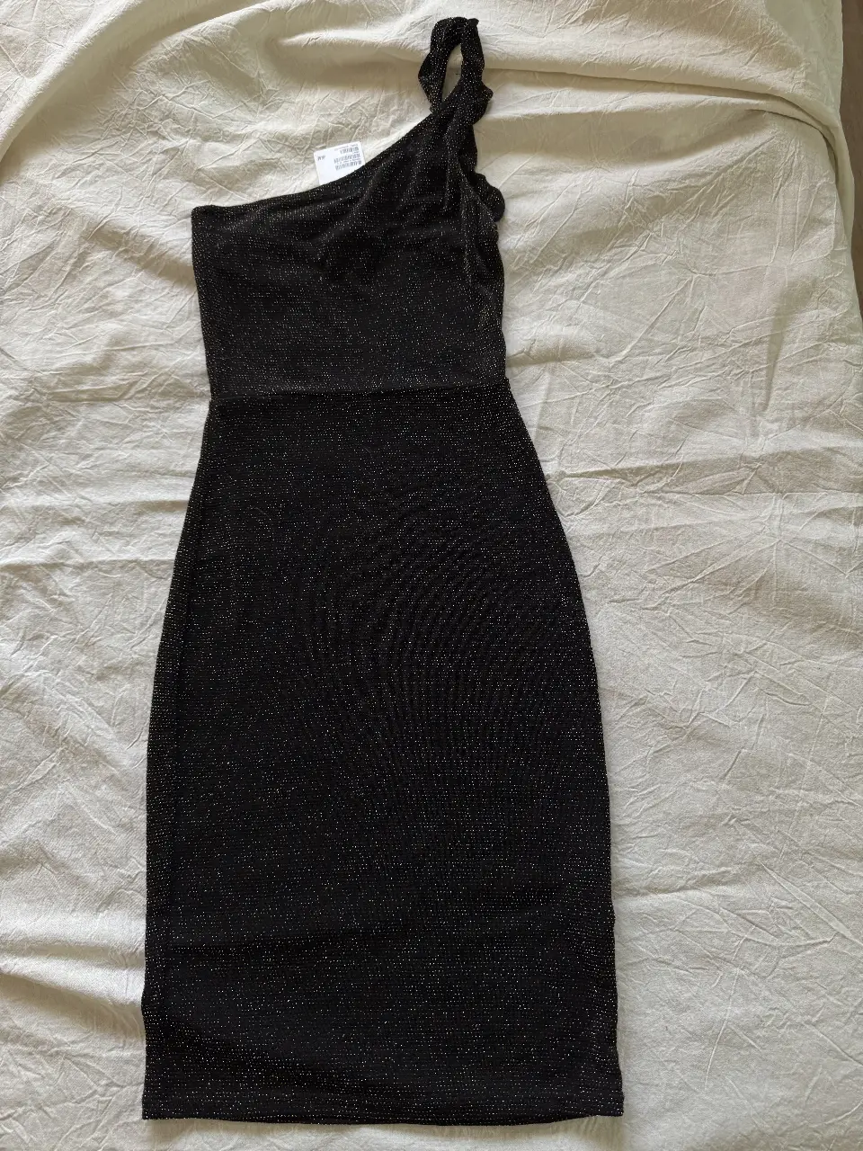 Vestido mini negro con brillos, de un solo hombro y detalle de volado en la manga. Ideal para fiestas y eventos.