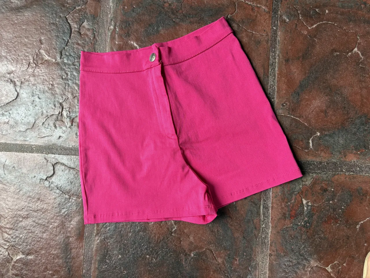 Shorts de vestir color fucsia, tiro alto, con un botón y cierre al frente. Ideales para un look canchero y moderno.