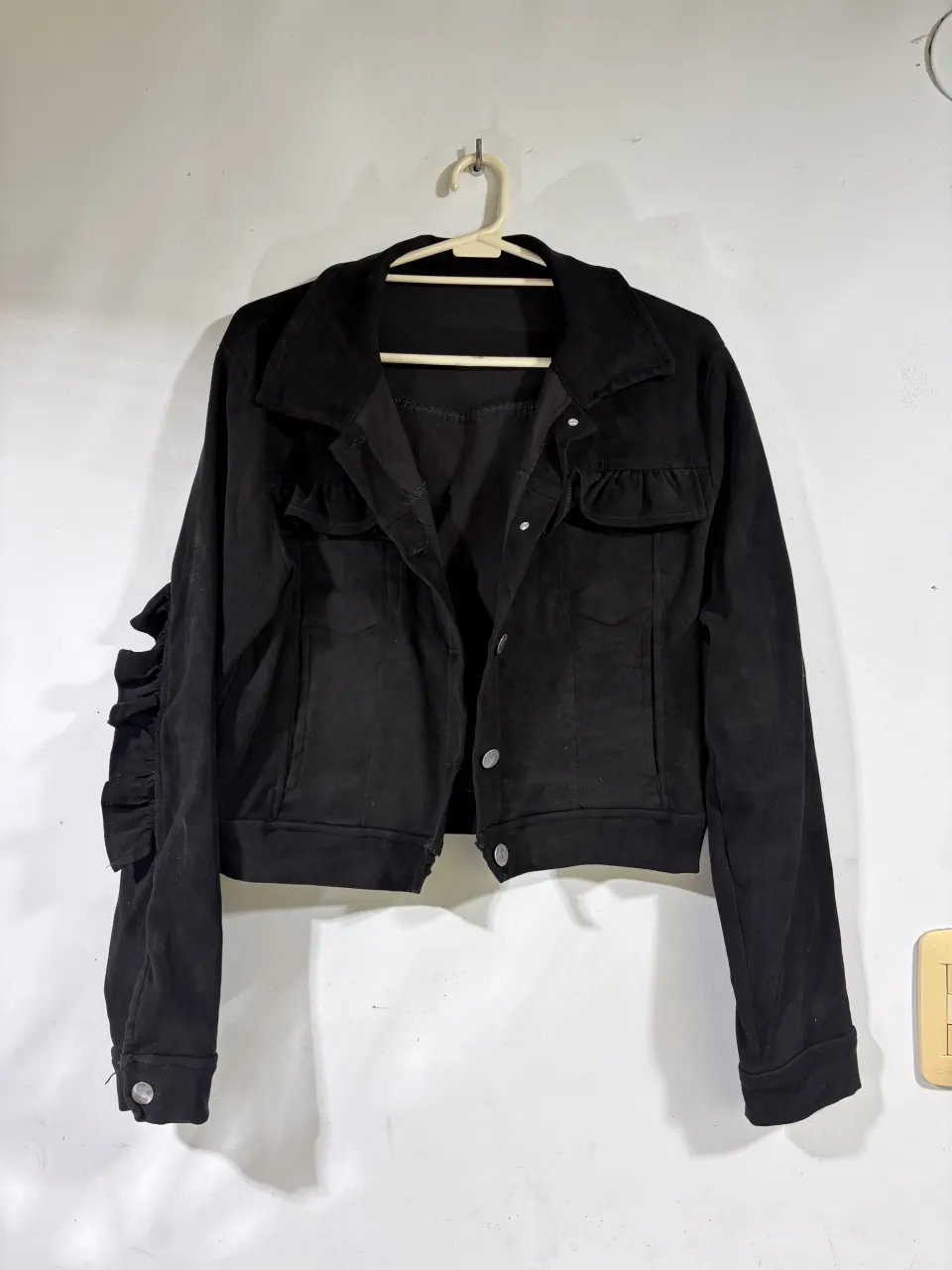 Campera negra corta con detalles de volados en las mangas y bolsillos. Ideal para un look canchero y moderno.