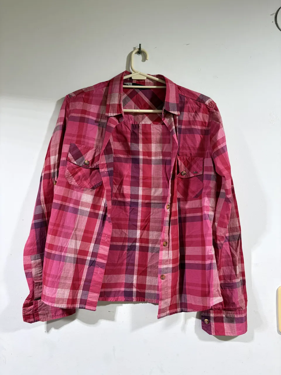 Camisa a cuadros de manga larga en tonos de rosa y fucsia. Posee dos bolsillos en el frente y botones para cerrar. Ideal para un look casual y cómodo.