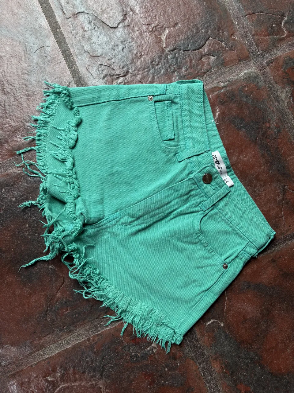 Shorts de jean color verde menta con roturas y flecos en el bajo. Tiro alto, ideales para un look canchero y veraniego.