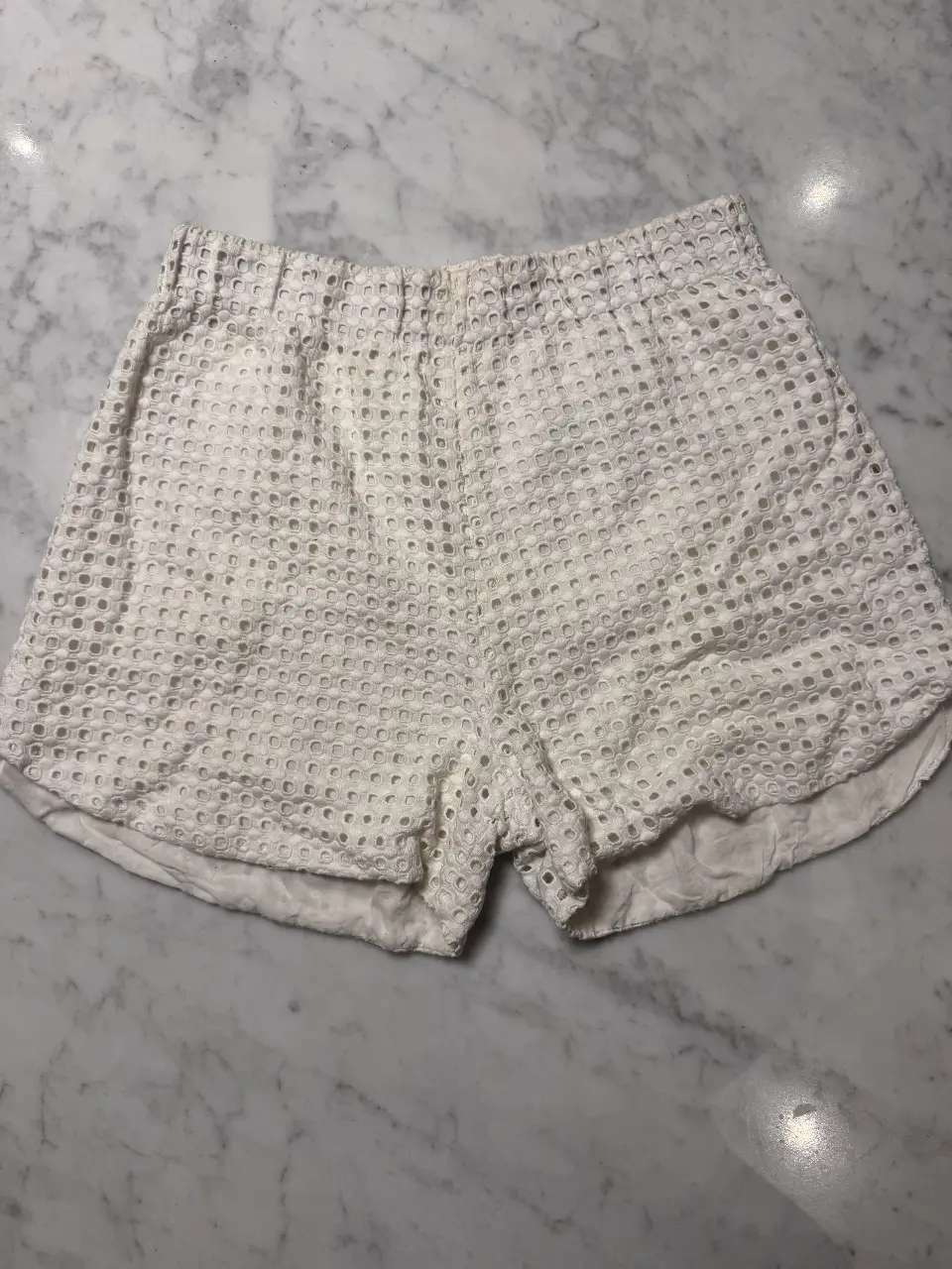 Shorts blancos de mujer, con diseño calado y cintura elastizada. Ideal para un look fresco y cómodo.