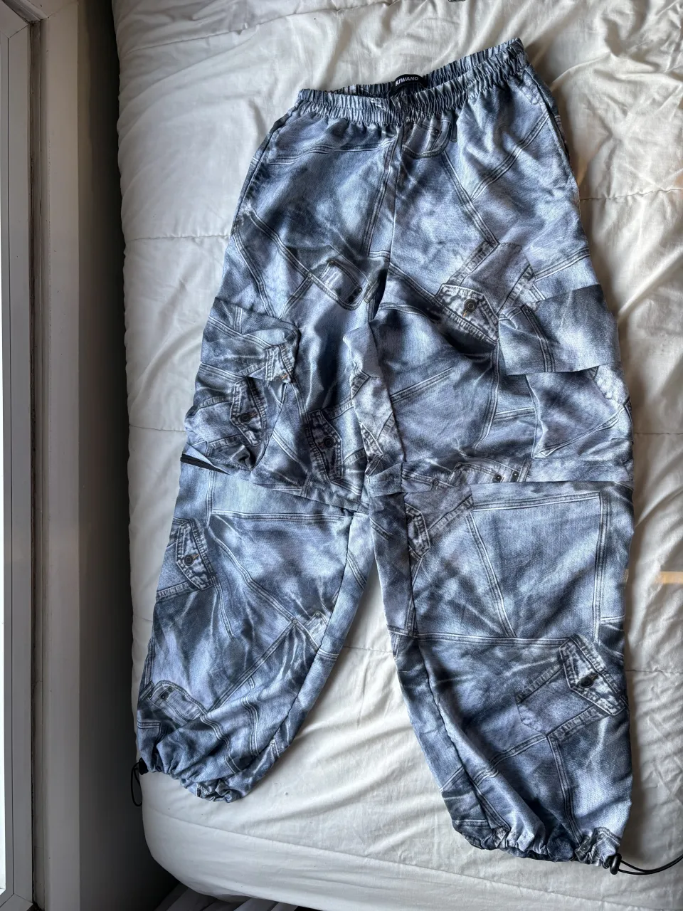 Pantalón largo con estampado de jean. Cintura elastizada con cordón. Bolsillos cargo a los costados. Tiene cierre a la altura de las rodillas para hacerlo bermuda.