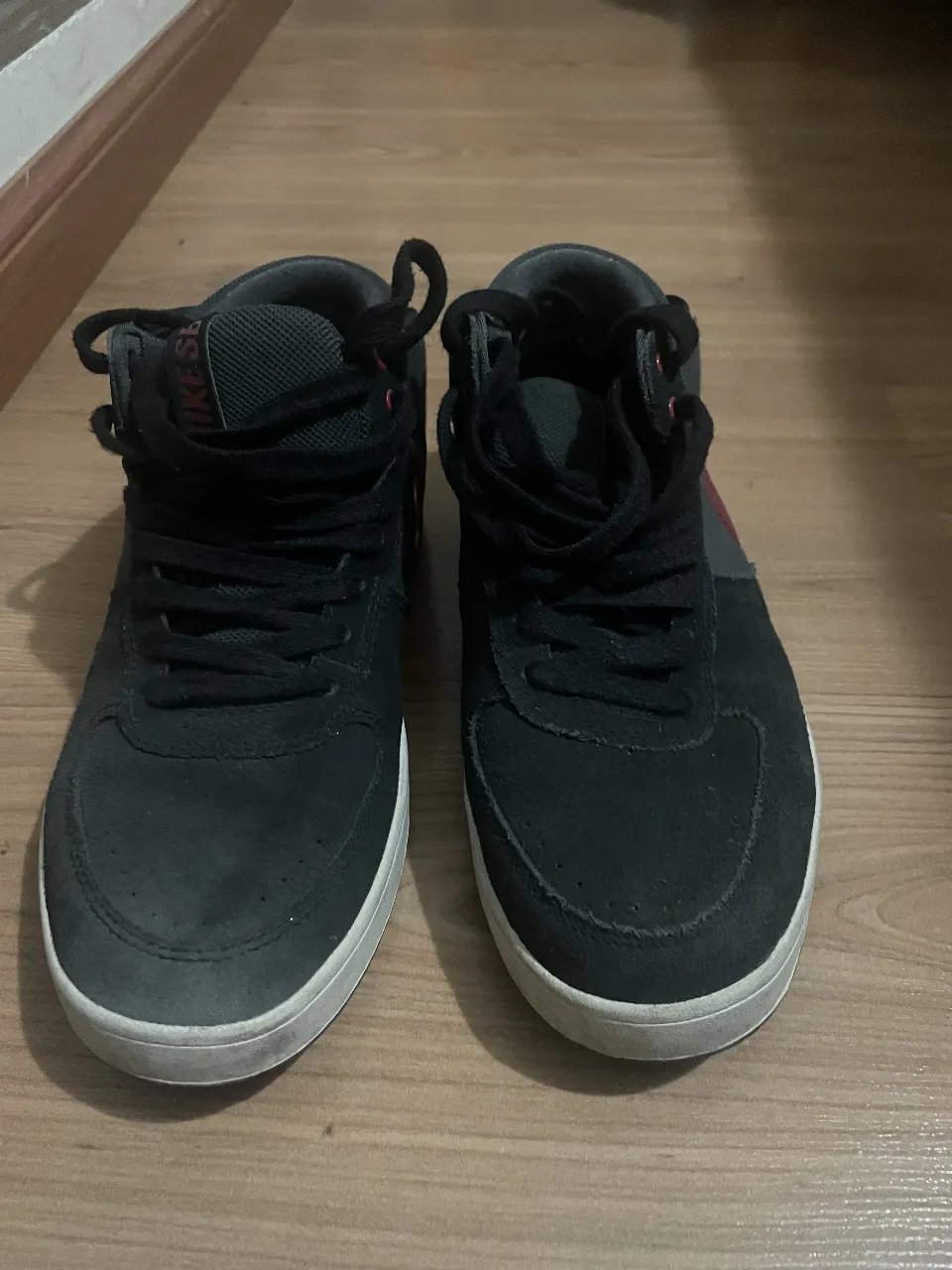 Zapatillas Nike SB de caña alta en color negro con detalles en rojo. Ideales para un look skater o casual.