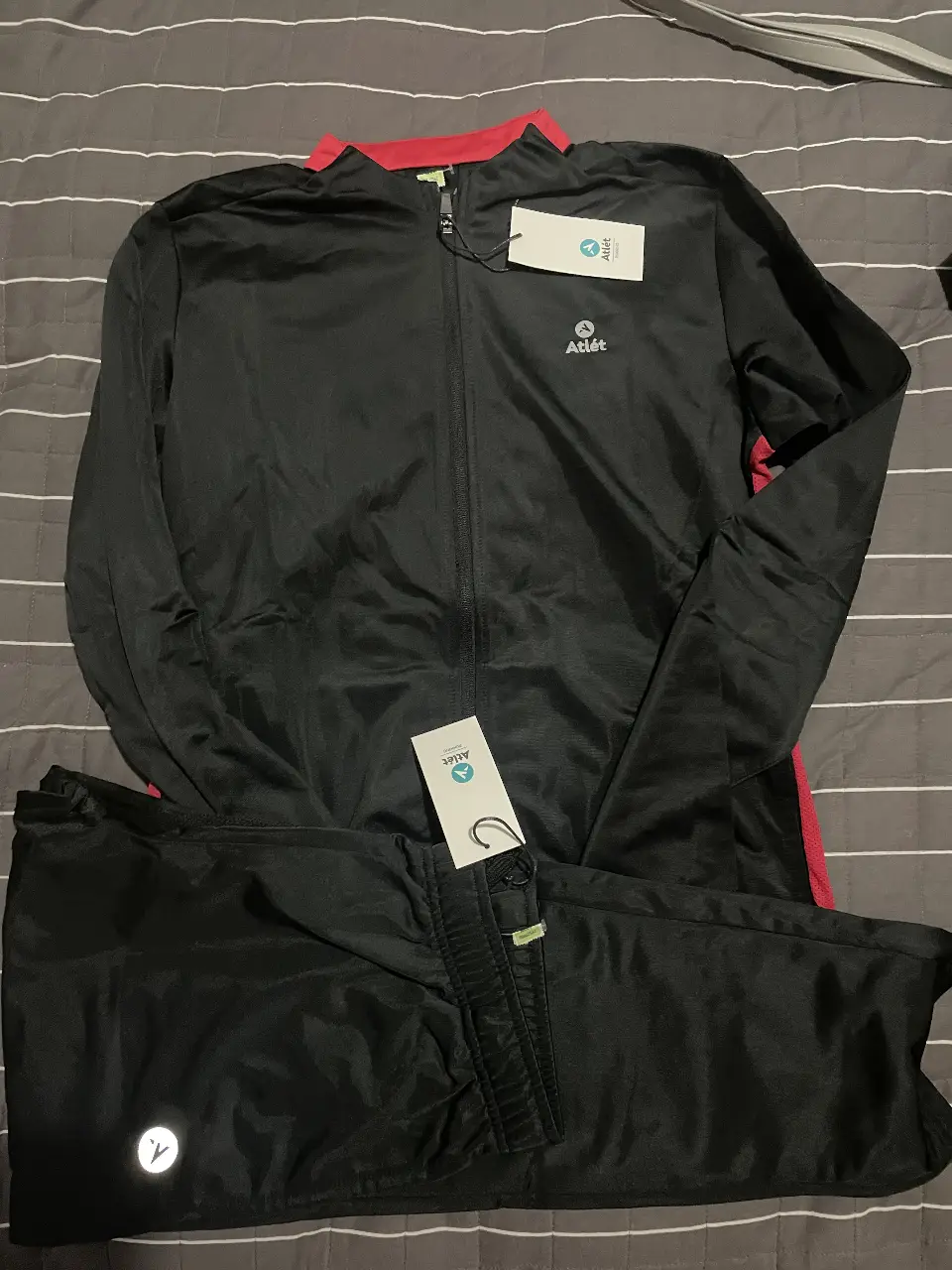 Conjunto deportivo de hombre, color negro con detalles en rojo. Incluye buzo con cierre y pantalón. Ideal para running y actividades deportivas.