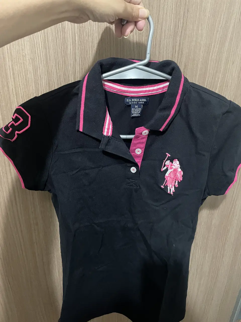 Remera deportiva de mujer US Polo Assn. en color negro con detalles rosas. Talle M. Ideal para actividades deportivas o uso casual.