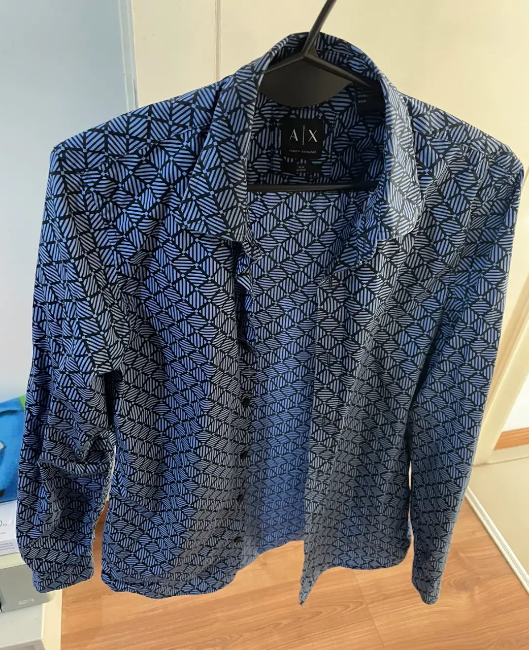 Camisa estampada de hombre, manga larga, con diseño geométrico en tonos azul y negro. Marca Armani Exchange, ideal para un look casual o semi-formal.