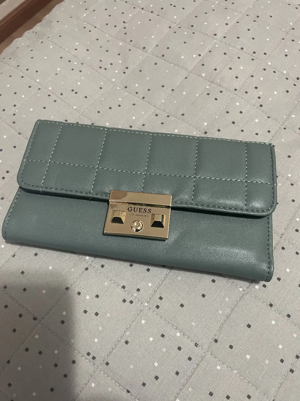 Billetera Guess de mujer, color verde, con cierre y detalles acolchados. Ideal para llevar tus esenciales con estilo.