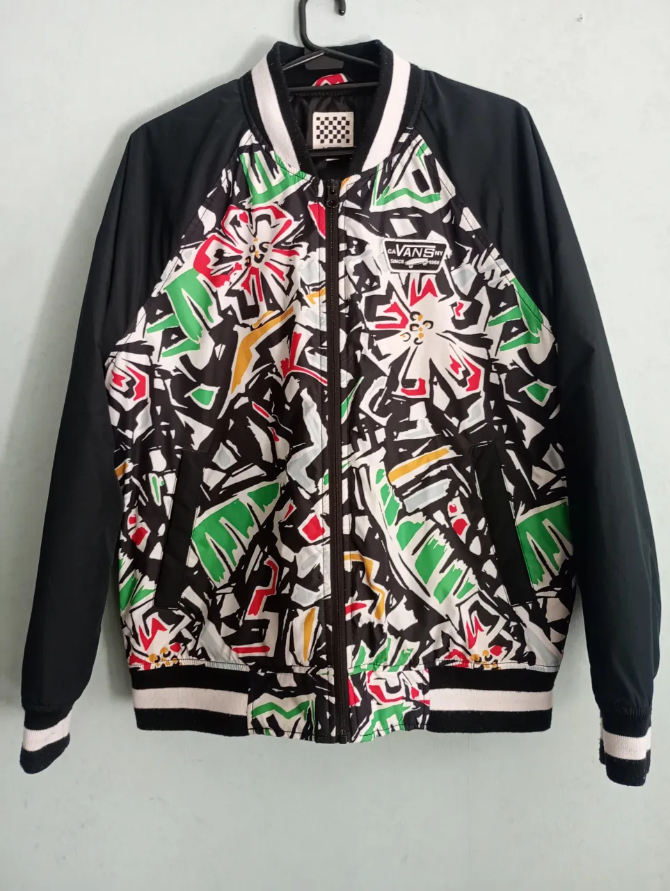 Campera bomber de Vans con un estampado súper original y colorido en el frente y la espalda. Mangas y espalda en negro, con puños y cuello a rayas. ¡Un diseño único para destacar!