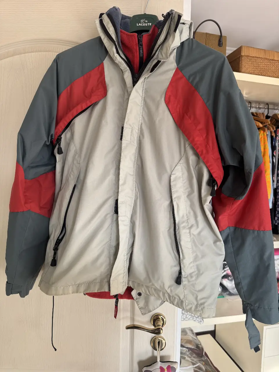Campera deportiva Globe, con cierre y capucha. Posee múltiples bolsillos y un forro interior de polar rojo. Ideal para actividades al aire libre en climas fríos.