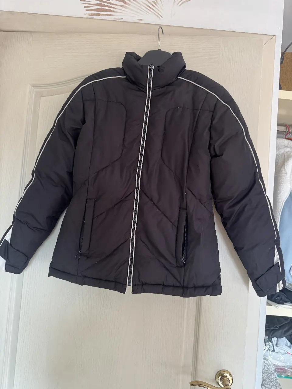 Campera negra acolchada con detalles blancos. Ideal para el invierno, con cierre y bolsillos.