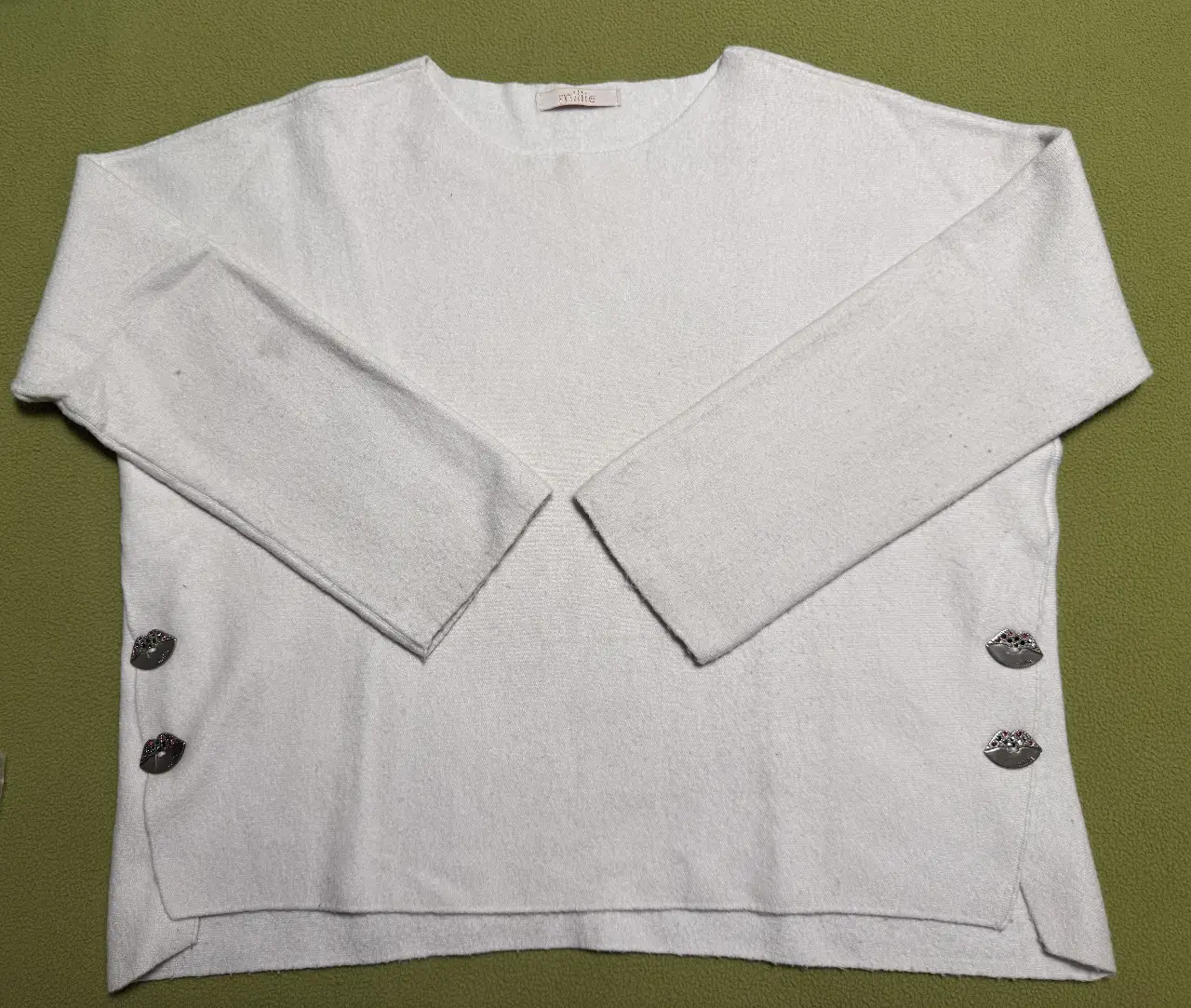 Sweater largo de punto blanco con detalles de botones en los laterales. Ideal para un look casual y cómodo.