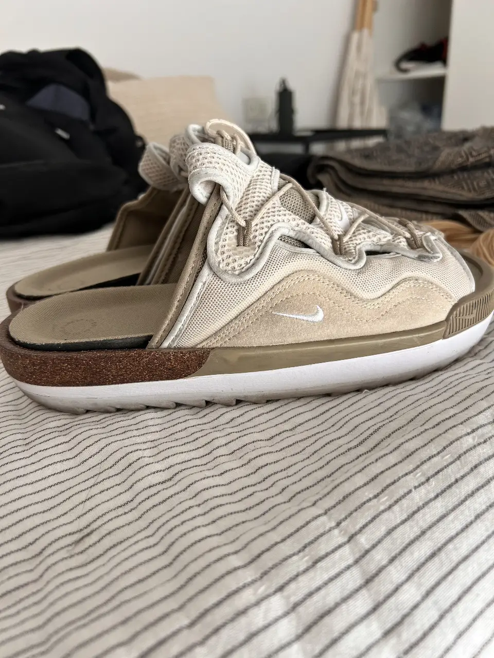 Sandalias Nike tipo ojotas, con diseño moderno y detalles en beige y marrón. Ideales para un look casual y cómodo.