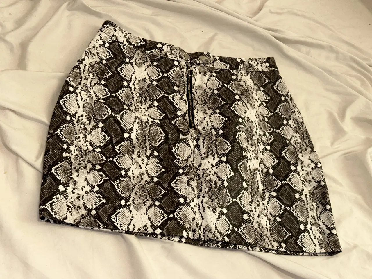 Pollera con estampado de serpiente, con cierre frontal. Ideal para un look moderno y audaz.