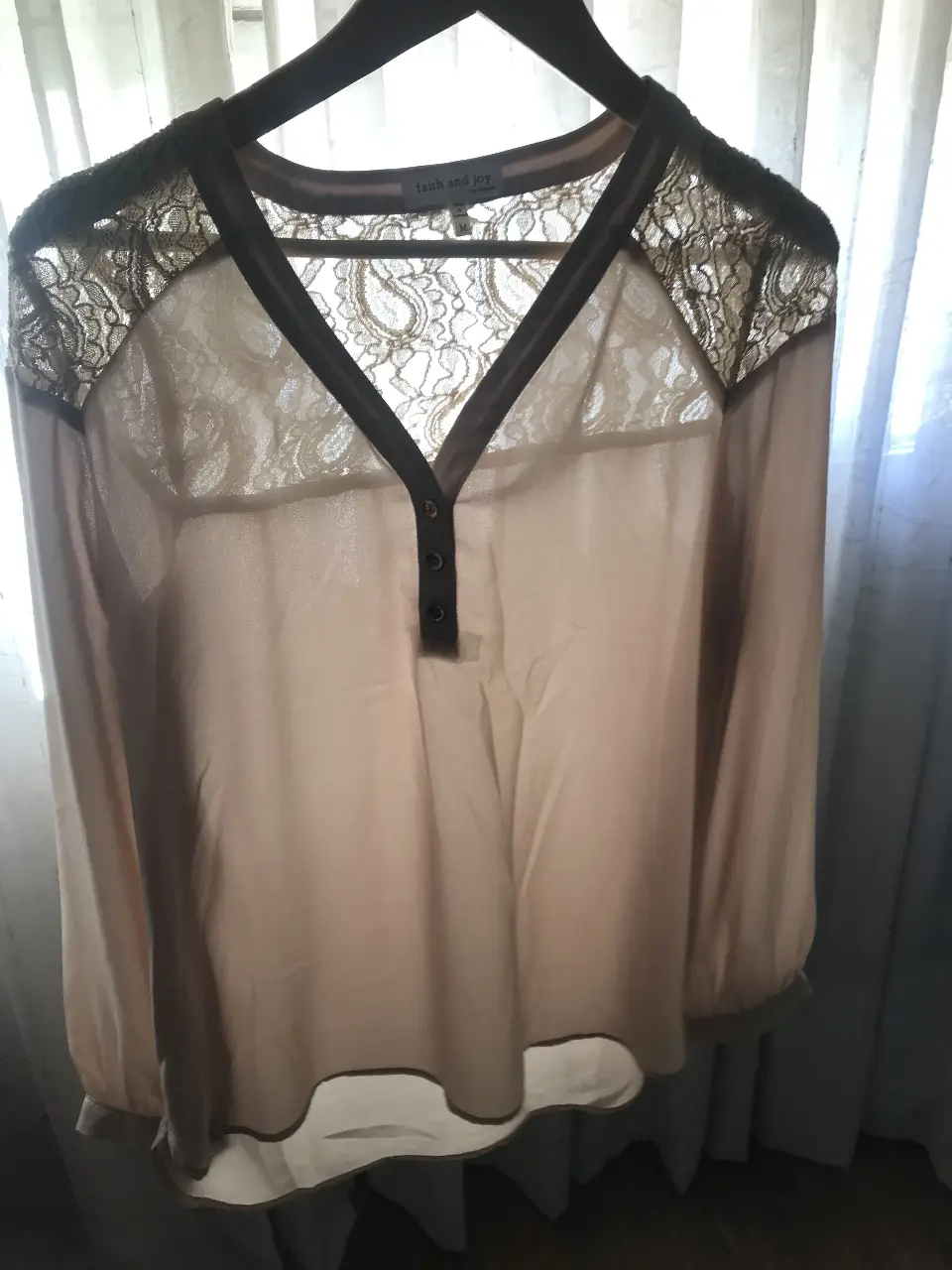 Blusa de mujer color crudo con detalles de encaje en los hombros y escote en V. Tiene mangas largas con puños abotonados y tres botones en la parte delantera. Marca Faith and Joy, talle M.