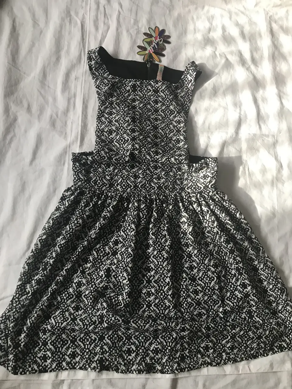 Vestido mini con estampado geométrico en blanco y negro. Diseño sin mangas y corte en la cintura, ideal para un look fresco y moderno. Perfecto para salir o eventos casuales.