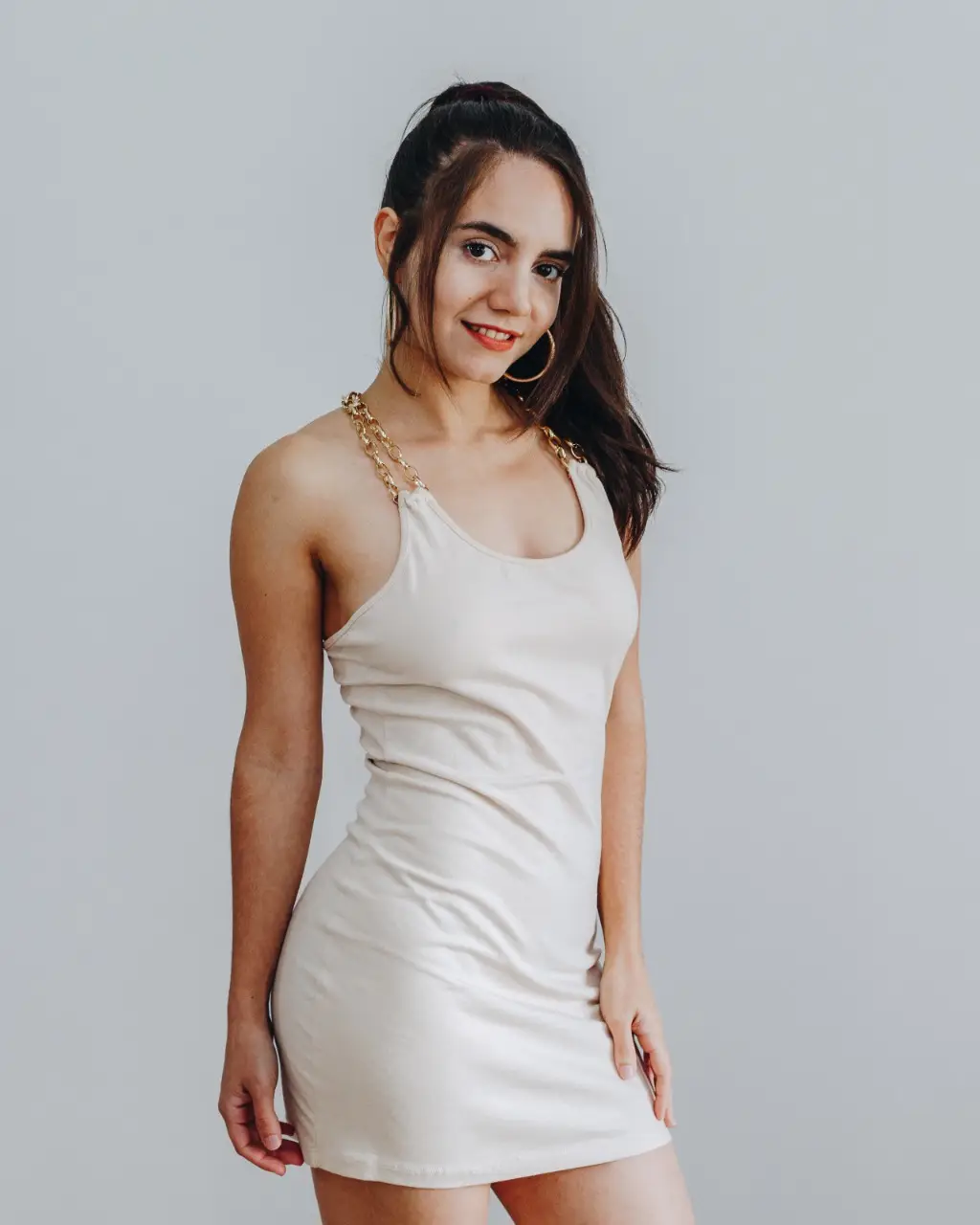 Vestido mini de mujer en color crudo, con tirantes dorados y detalles de cadena. Ideal para fiestas y salidas.