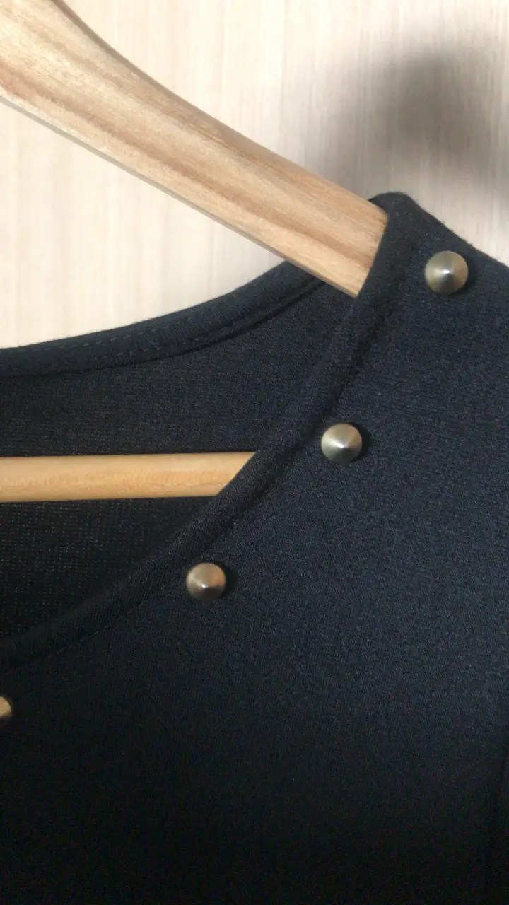 Vestido negro corto con mangas largas y detalles de botones dorados en el cuello. Ideal para una salida o evento especial.