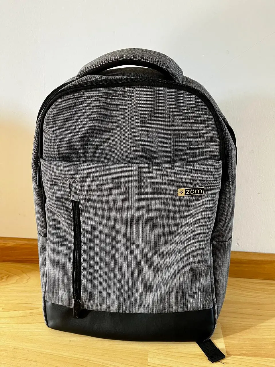 Mochila gris con detalles en negro, ideal para llevar tus cosas con estilo y comodidad. Cuenta con un bolsillo frontal con cierre, un compartimento principal amplio y bolsillos internos para organizar tus pertenencias. Perfecta para el día a día.