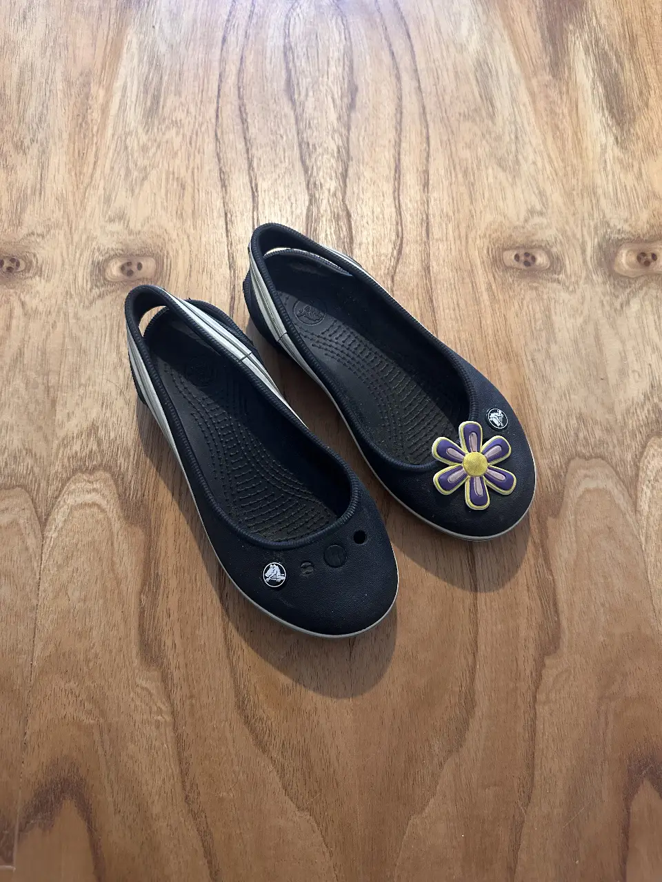 Ballerinas negras de Crocs con detalle de flor en la punta. Ideales para un look casual y cómodo.