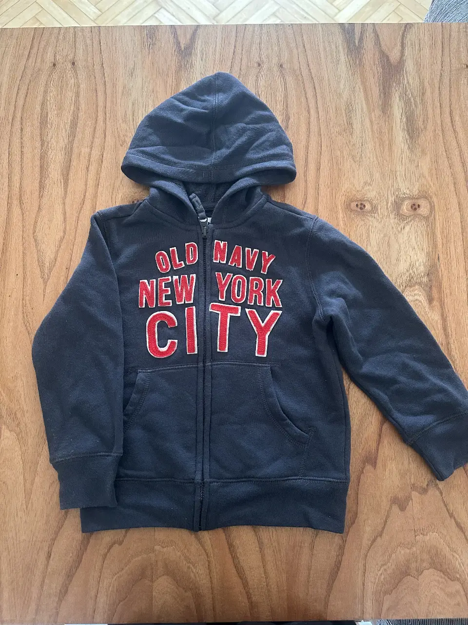Buzo con cierre Old Navy para nenes, color negro con letras rojas "New York City". Ideal para un look casual y abrigado.