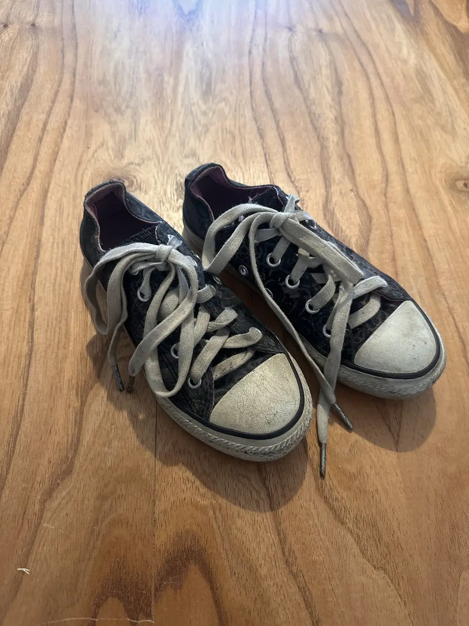 Zapatillas negras con detalles blancos en la puntera y cordones. Ideales para un look casual y urbano.