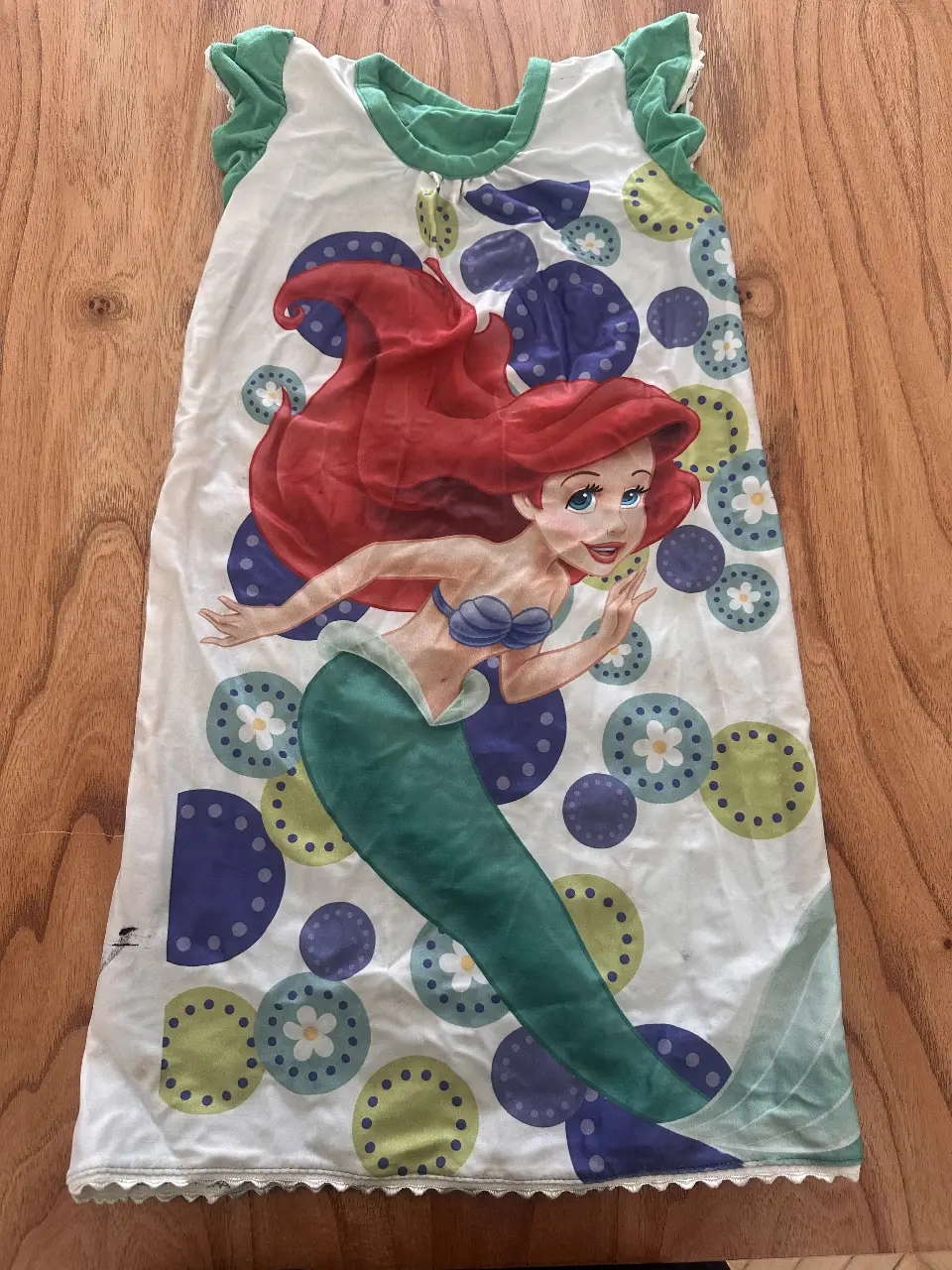 Vestido de niña con estampado de Ariel, la Sirenita. Diseño con volados en las mangas y detalles de encaje en el borde inferior. Ideal para un look casual y divertido.
