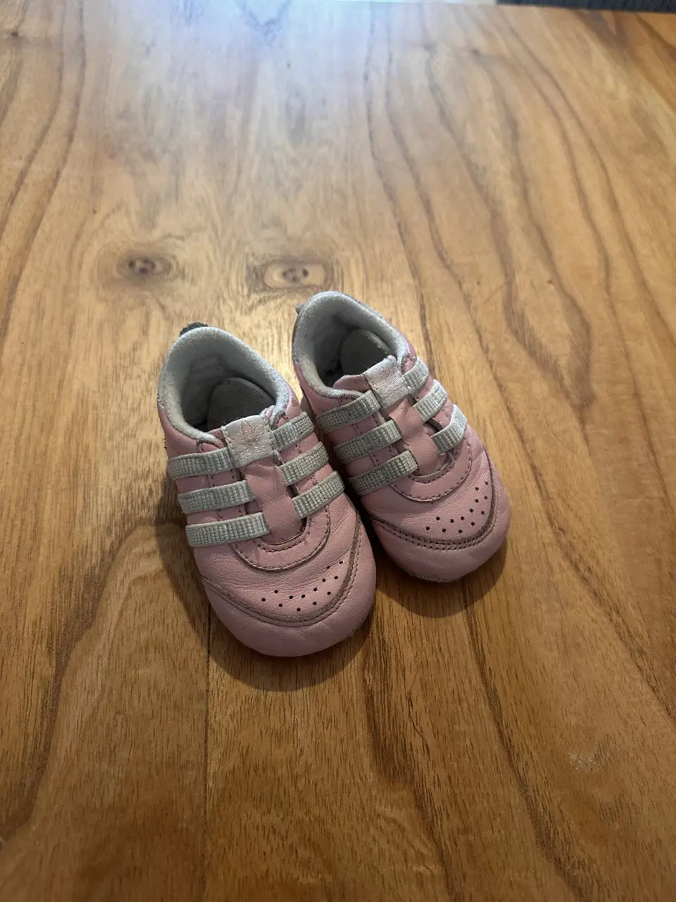 Zapatillas de bebé color rosa con detalles en gris. Ideales para los primeros pasos, cómodas y con un diseño clásico.