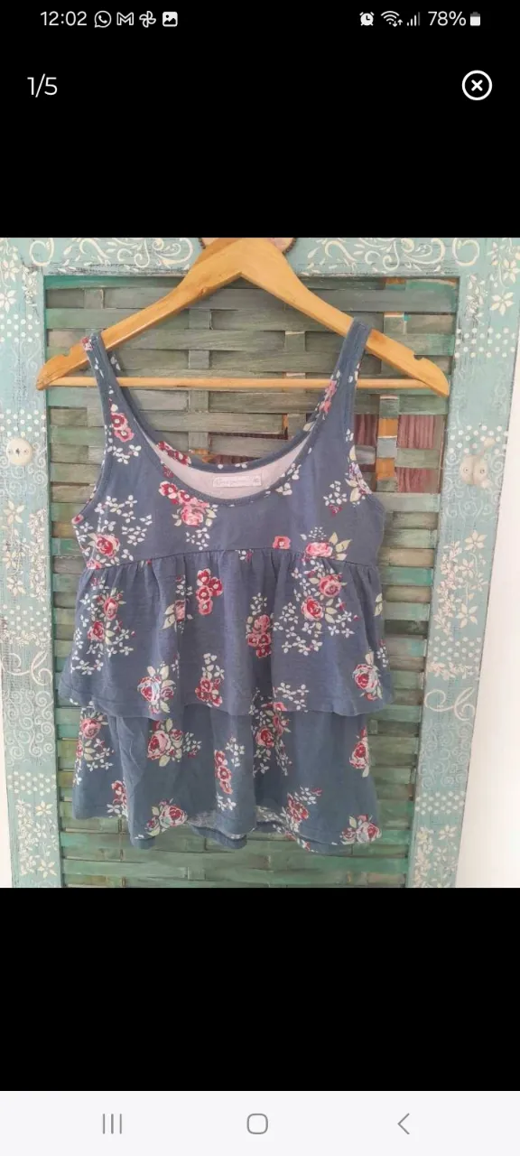 Top de mujer con estampado floral en tonos rojos y blancos sobre fondo azul. Diseño con volados y breteles finos. Talle 40.