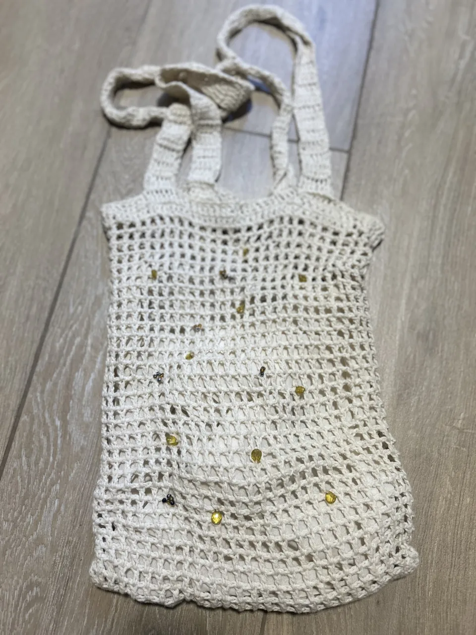 Bolso tejido al crochet, color crudo, con detalles de mostacillas amarillas y negras. Ideal para llevar tus esenciales con un toque bohemio y chic. Perfecto para el día a día, salidas casuales o para complementar tu look de playa.