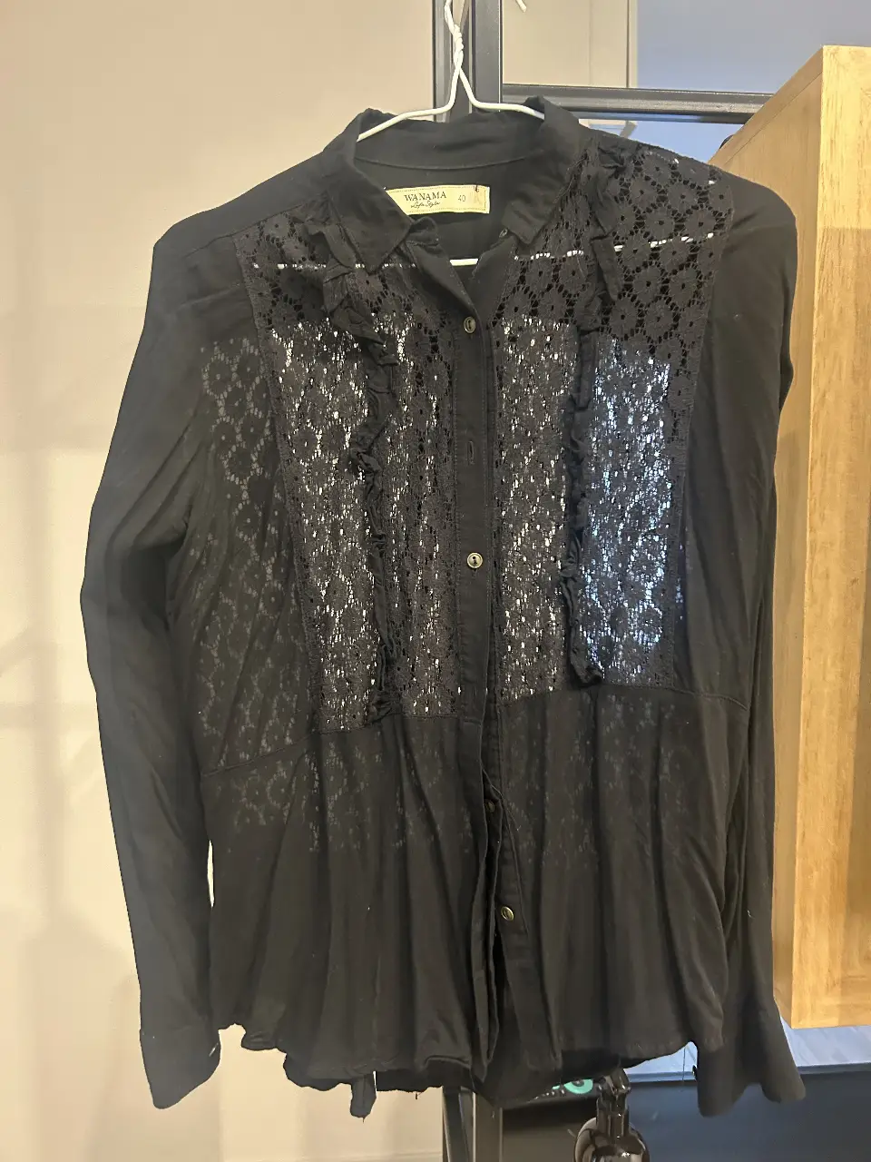Blusa negra de la marca Wanama, con detalles de encaje en el frente y espalda. Ideal para un look elegante y sofisticado.