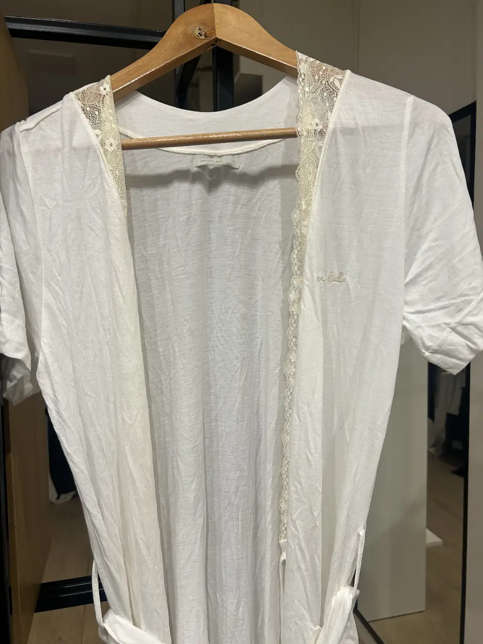 Bata blanca con detalles de encaje y la inscripción "bonjour lulu". Ideal para un look casual y fresco.