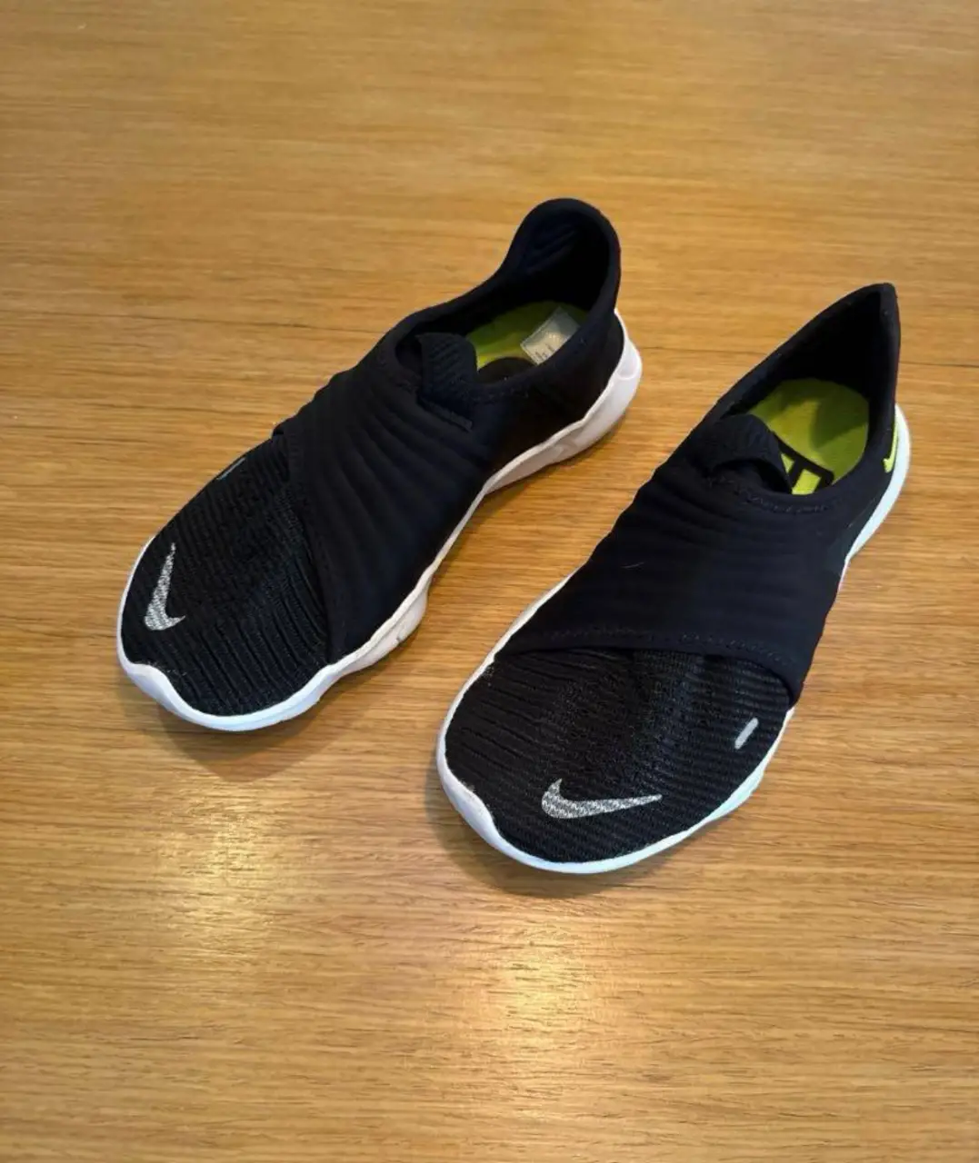 Zapatillas Nike Free sin cordones, color negro con detalles en blanco y amarillo. Diseño moderno y cómodo, ideales para uso diario y actividades deportivas.