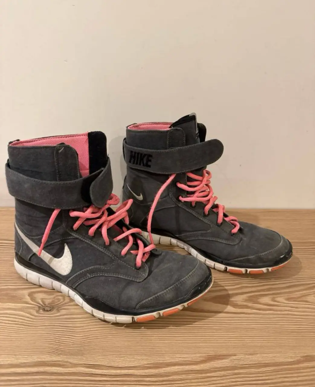 Botines Nike Free Trainer 1.0 de color gris con detalles en rosa y blanco. Ideales para entrenamientos y uso diario. Diseño moderno y cómodo.